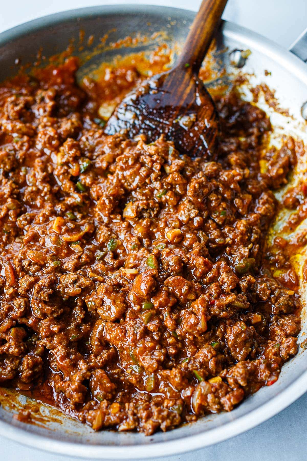 sloppy joe sauce added to pan with ground beef, mixed together with wooden spatula. 