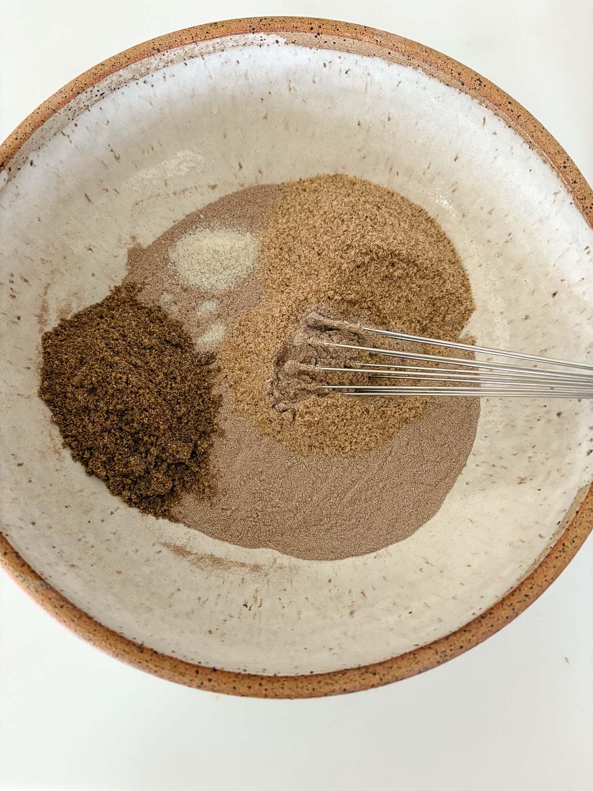 whisk mixing together dry gluten free bread ingredients like teff and flax seed.