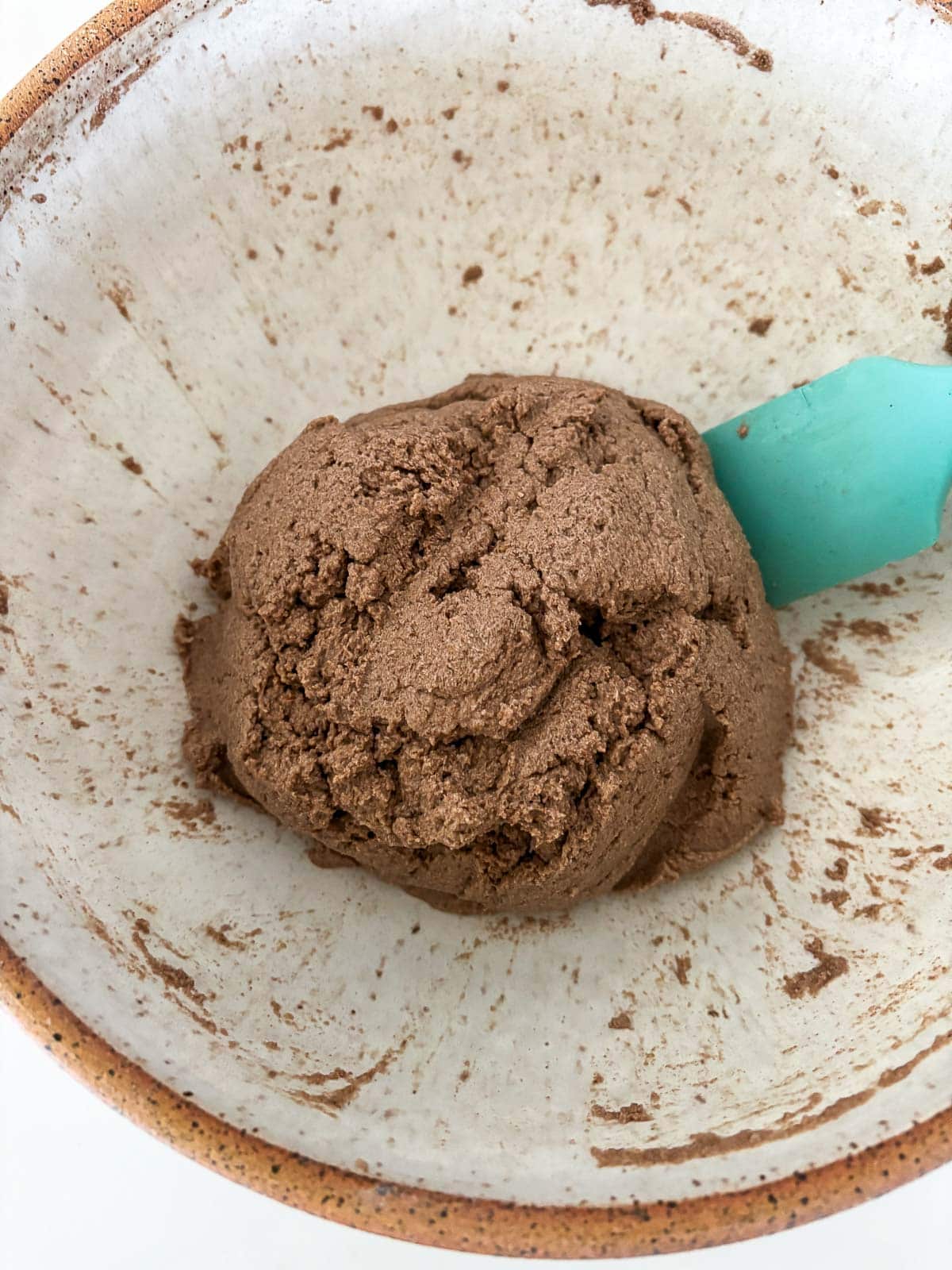 blue spatula next to a ball of gluten free bread dough in a bowl.