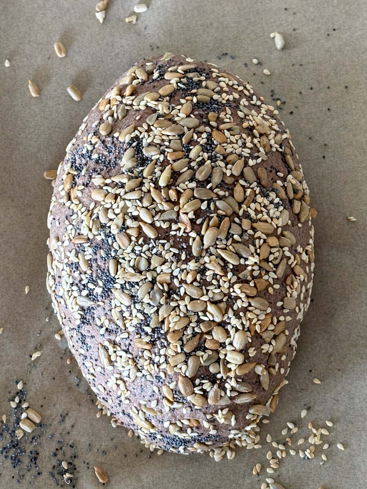 seeds pressed into gluten free bread dough unbaked on a parchment paper.
