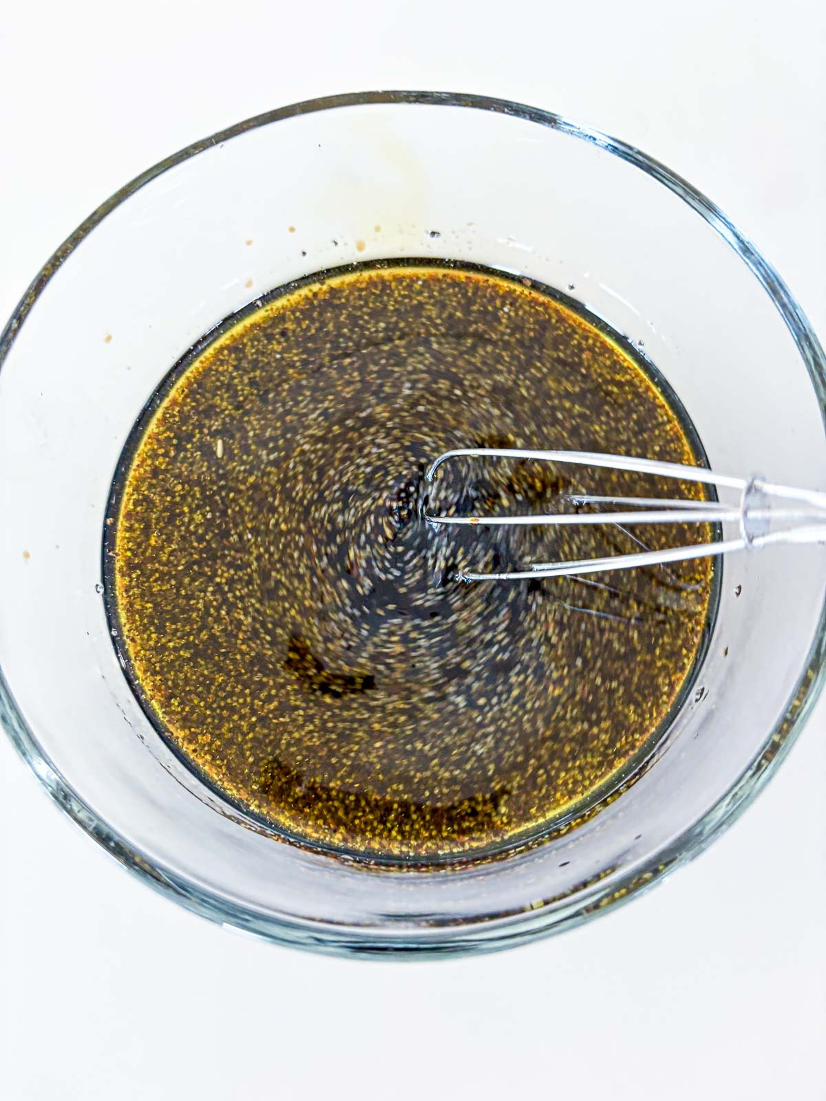 whisk stirring together vanilla-balsamic poppy seed dressing.