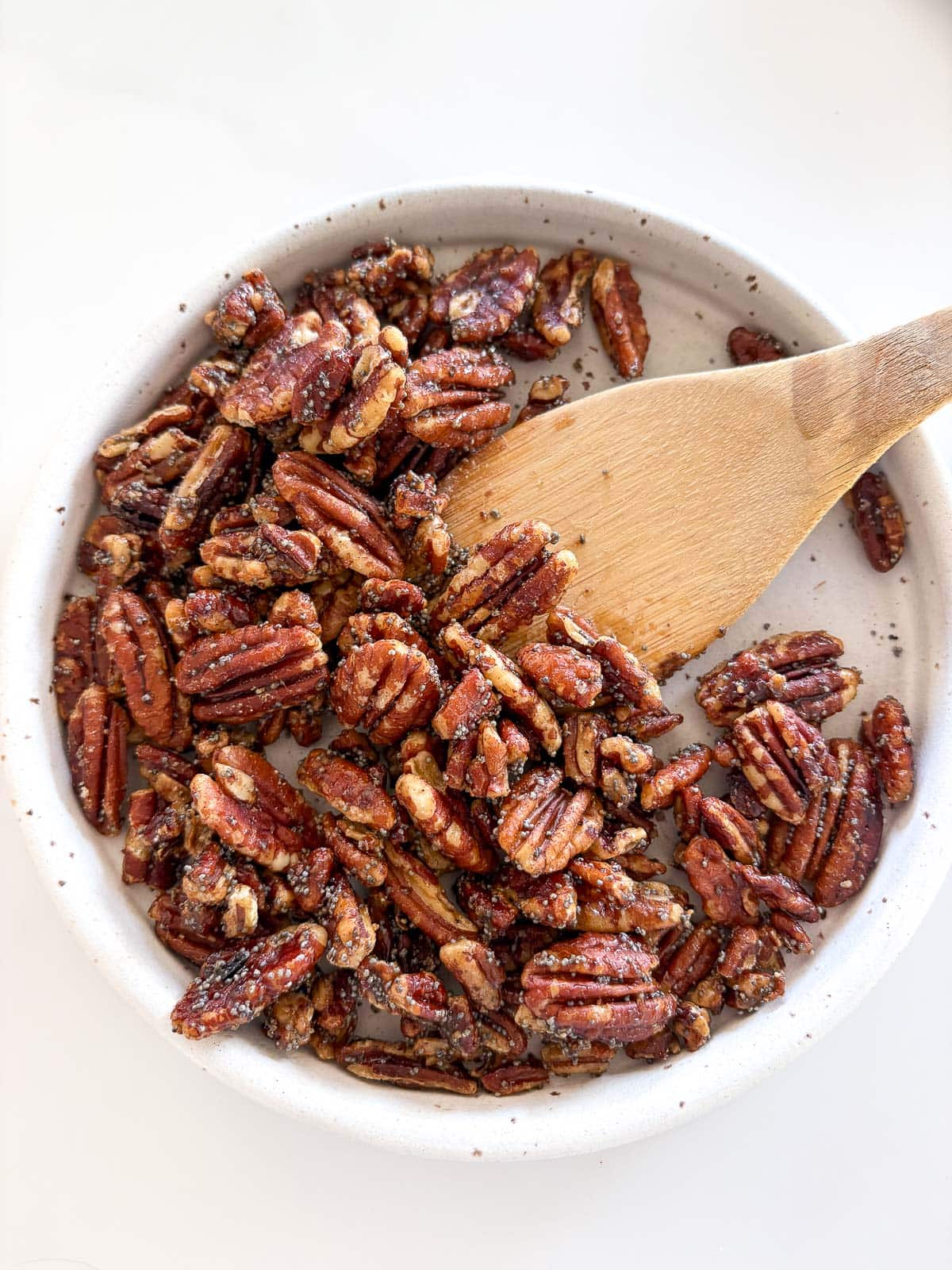 pecan brittle in ceramic dish with wood spatula scooping it up.