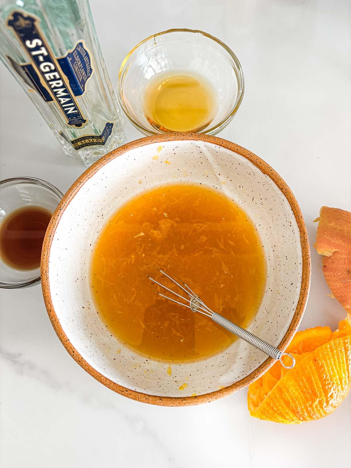 bowl of orange juice with vanilla and honey and st. germain with a whisk.