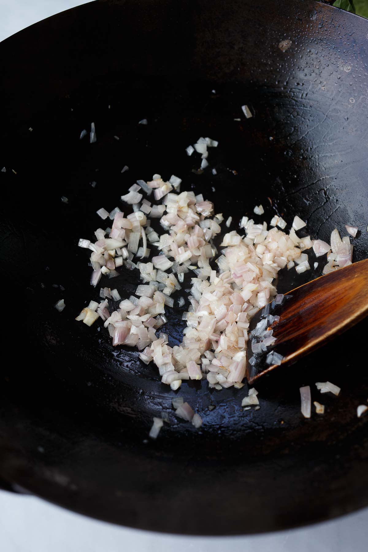 diced shallots in wok with wooden spoon.