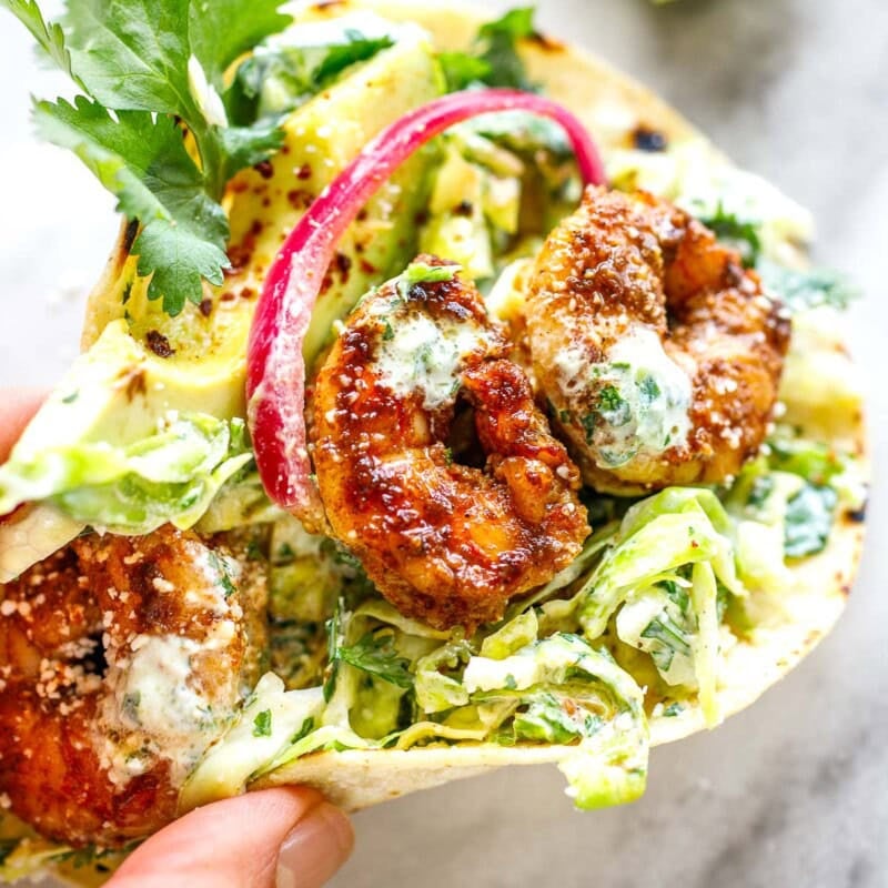 Spicy, flavorful shrimp tacos with fresh cilantro lime slaw, avocado, pickled onions and cilantro lime crema - a delicious and easy weeknight meal! Gluten-free adaptable.