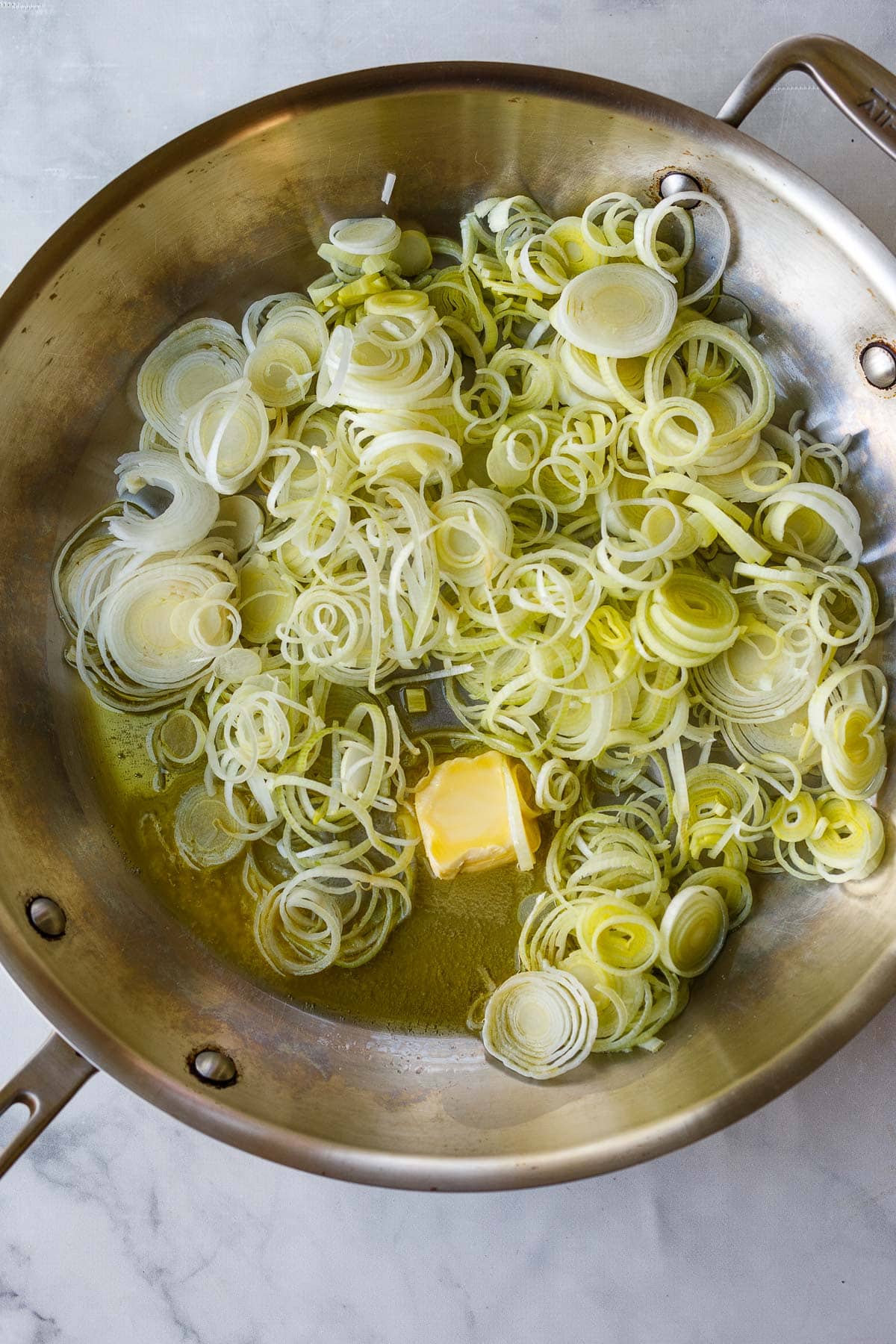 pan with a pat of butter and olive oil with white leek slices.