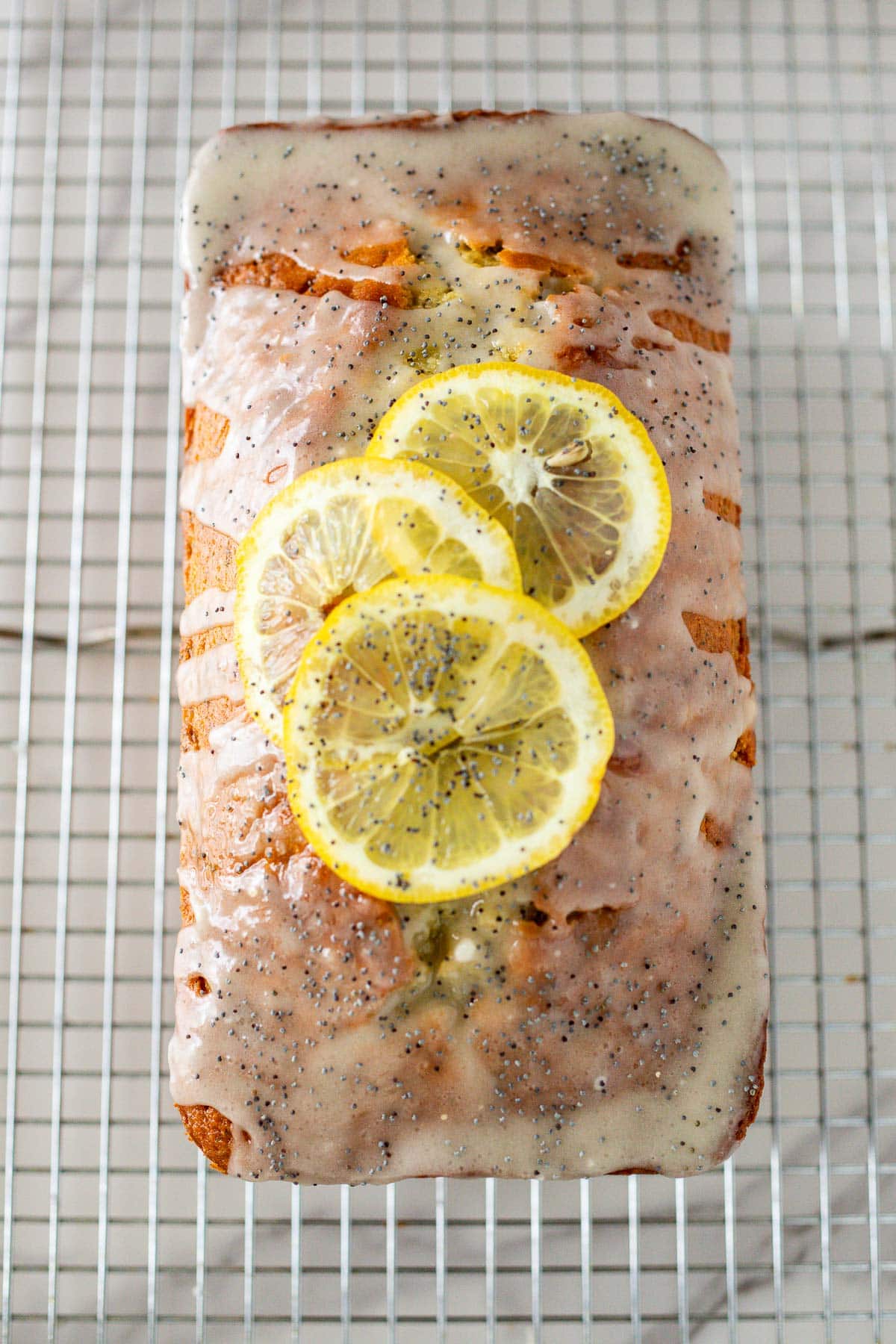 lemon poppy seed cake on wire rack with lemon glaze and lemon slices. 