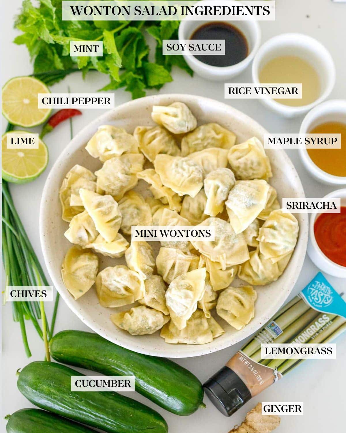 ingredients for wonton salad - bowl of frozen mini wontons, lemongrass paste, cucumbers, ginger, scallions, limes, red chili, mint and sauces. 