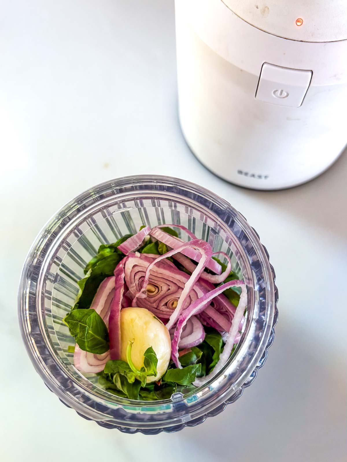 glass jar of blender with basil, lemon, shallots, and other ingredients to make basil vinaigrette.